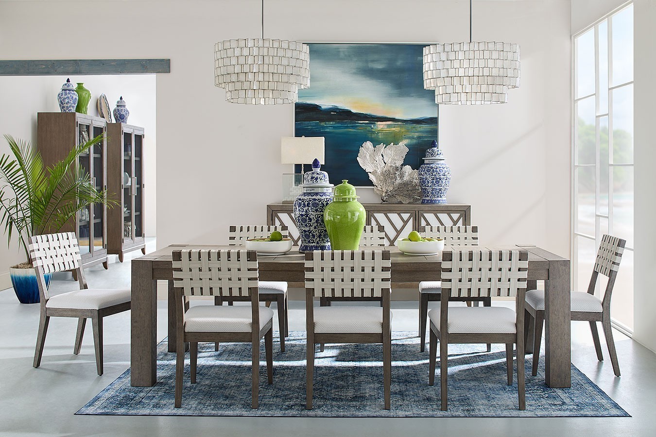 Dining room set with a wooden table and woven side chairs in a bright room.