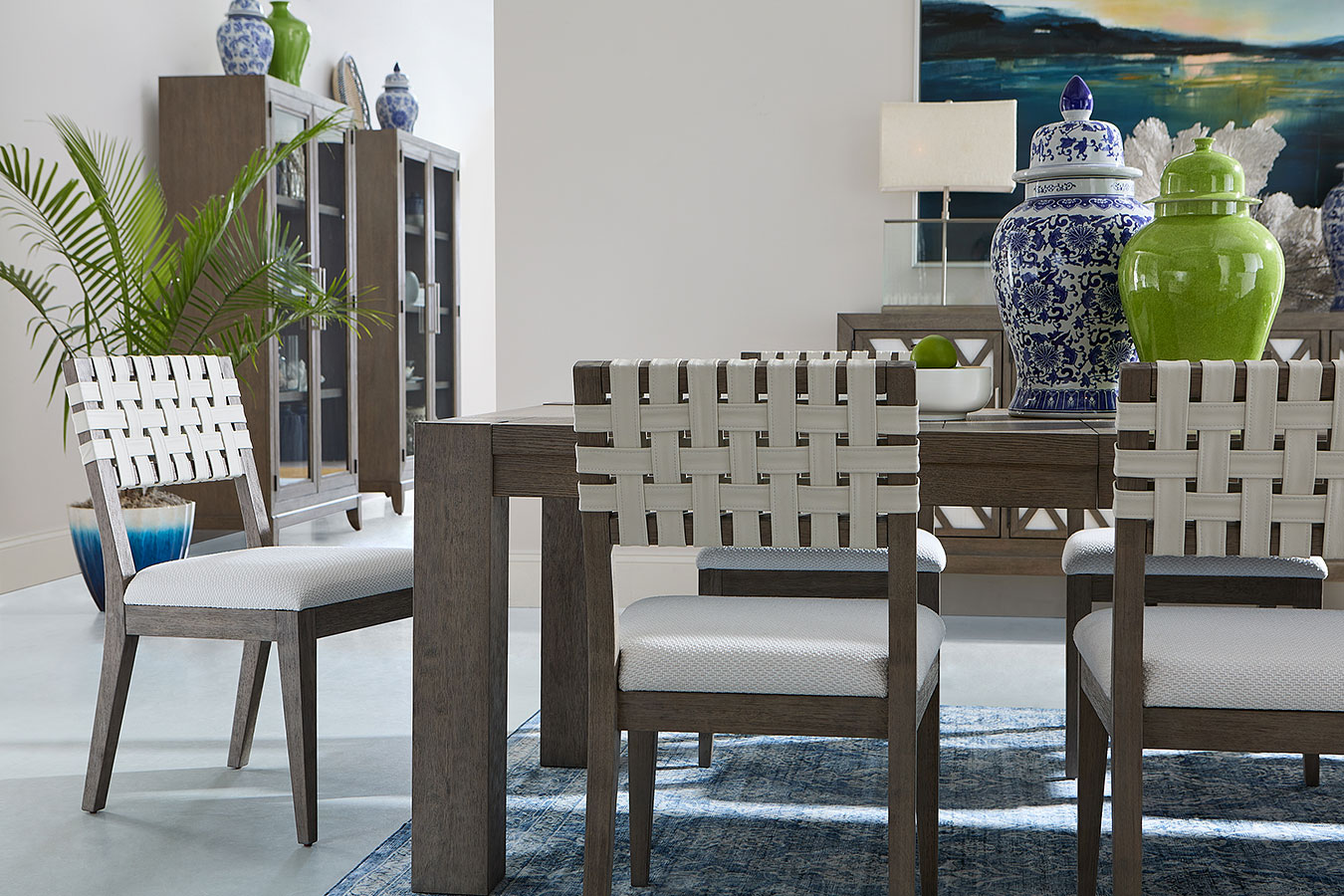 Dining room set with a wooden table and woven side chairs in a bright room.