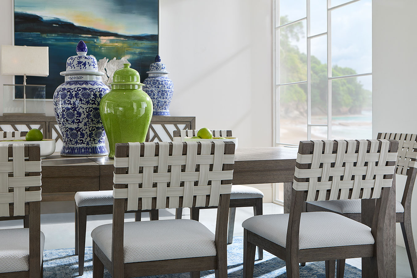 Dining room set with a wooden table and woven side chairs in a bright room.